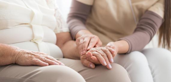 Oudere vrouw hand in hand met verzorgster